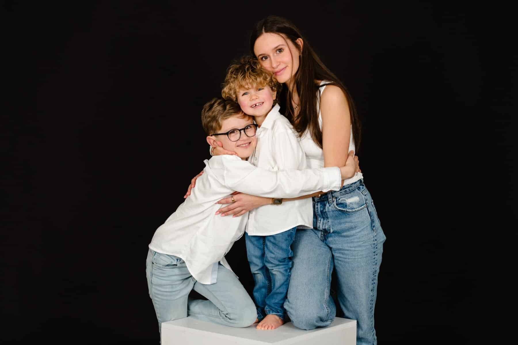 Trois frères et sœurs enlacés lors d’une séance photo au studio de Mouscron