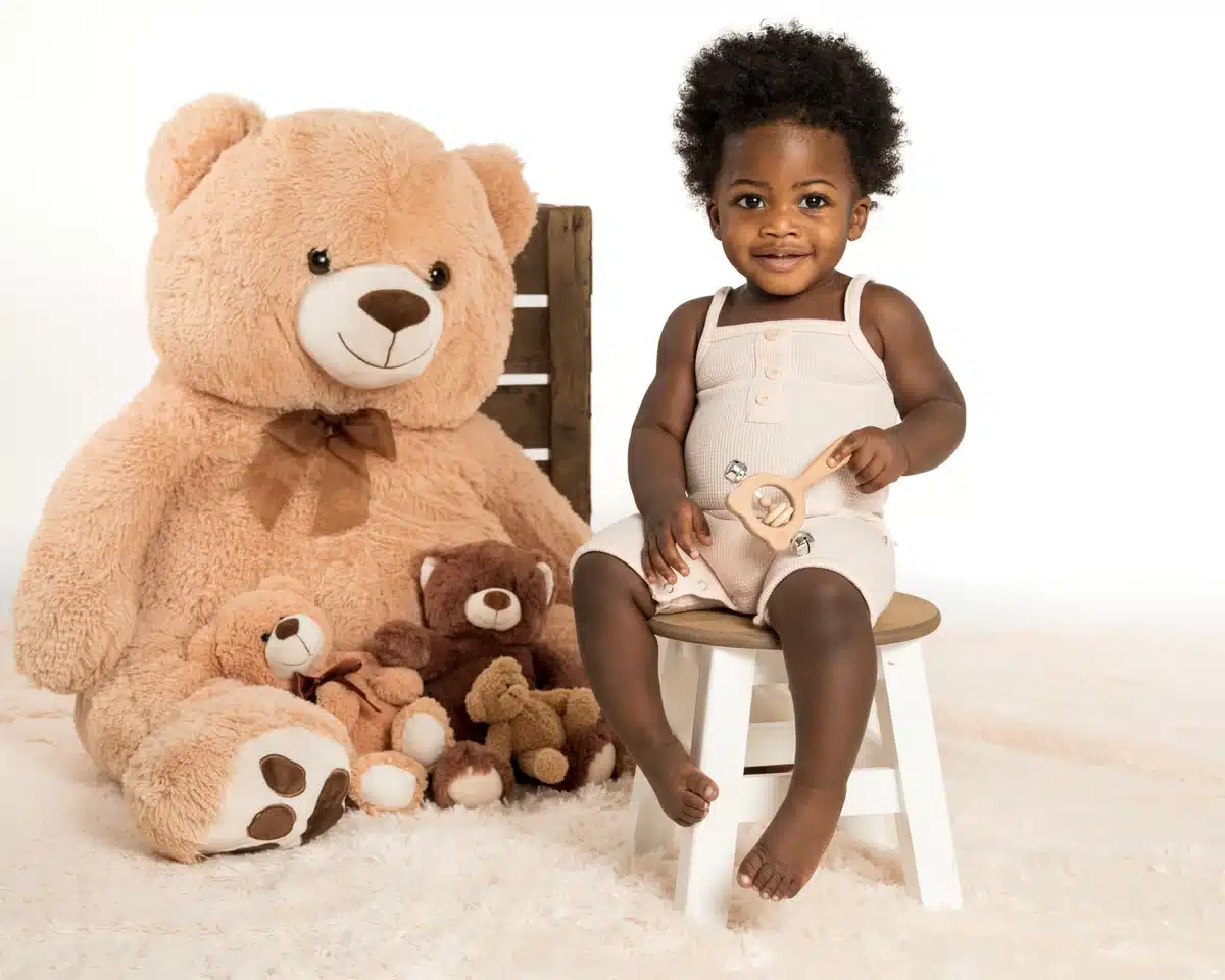 Enfant assis près d’un grand ours en peluche au studio à Mouscron