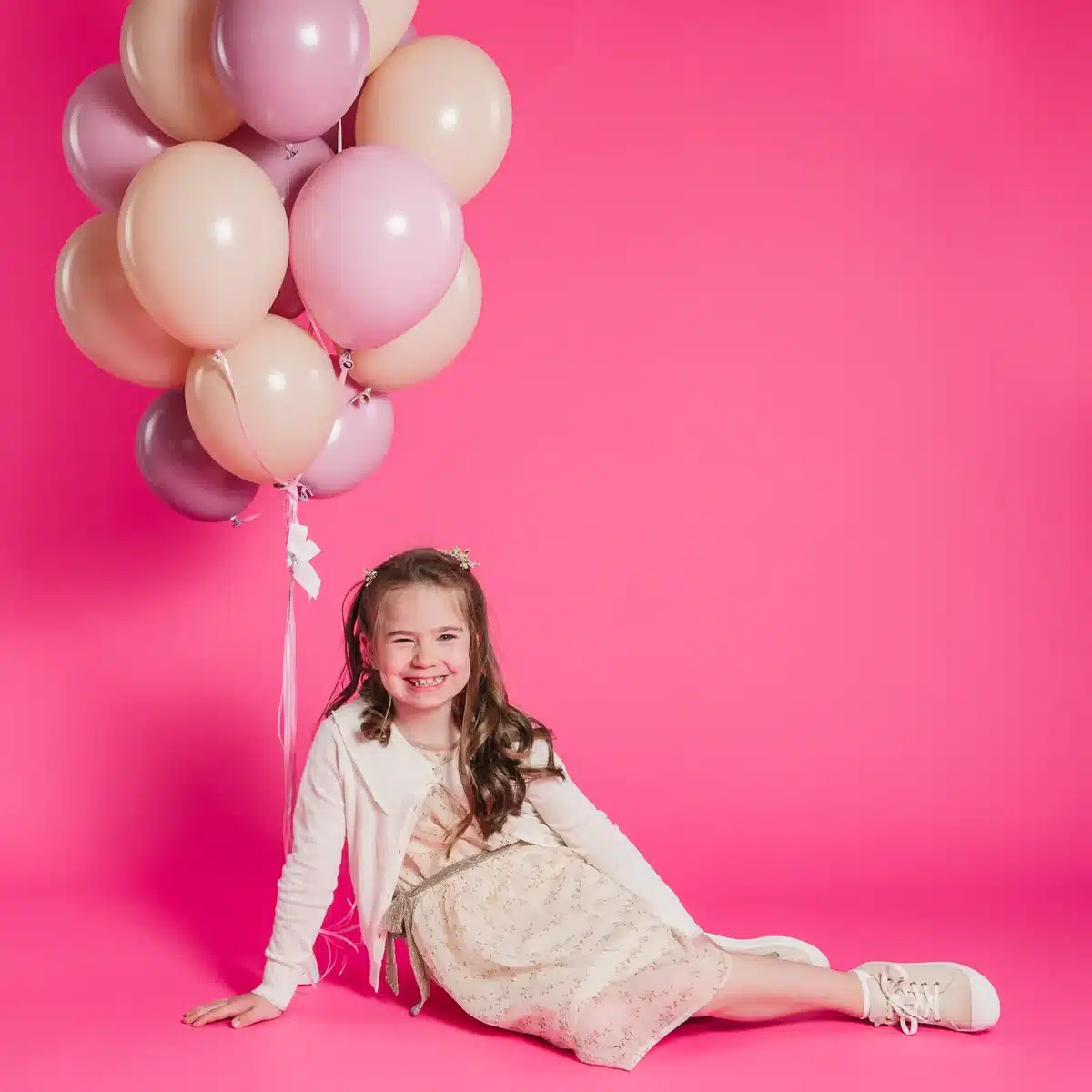 Petite fille avec des ballons roses lors d’une séance photo au studio