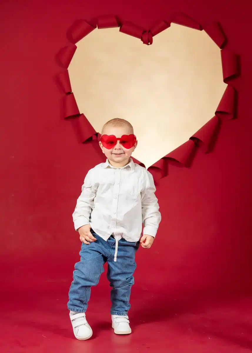 Petit garçon avec des lunettes rouges dans un décor en forme de cœur