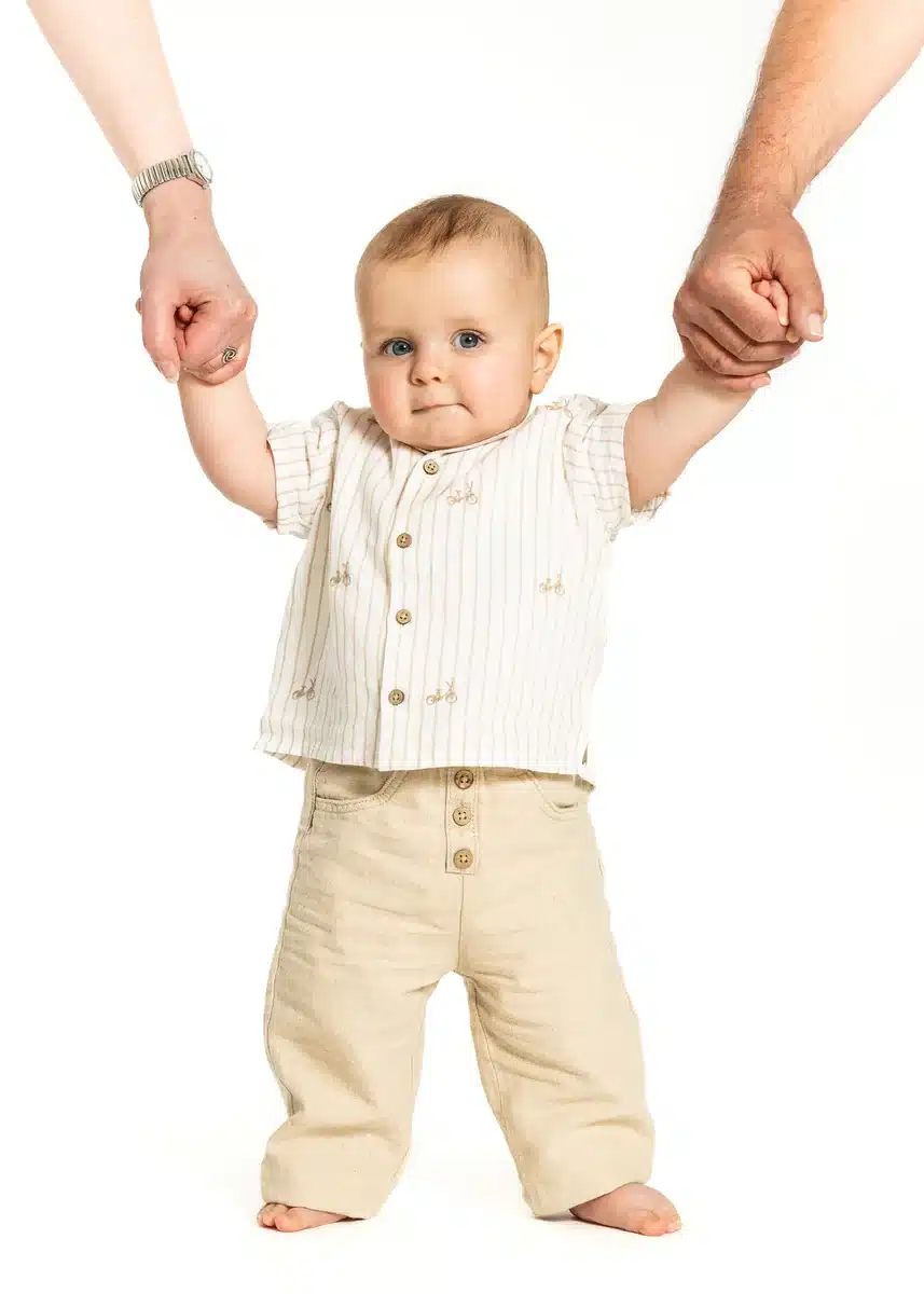 Bambin debout tenant les mains de ses parents